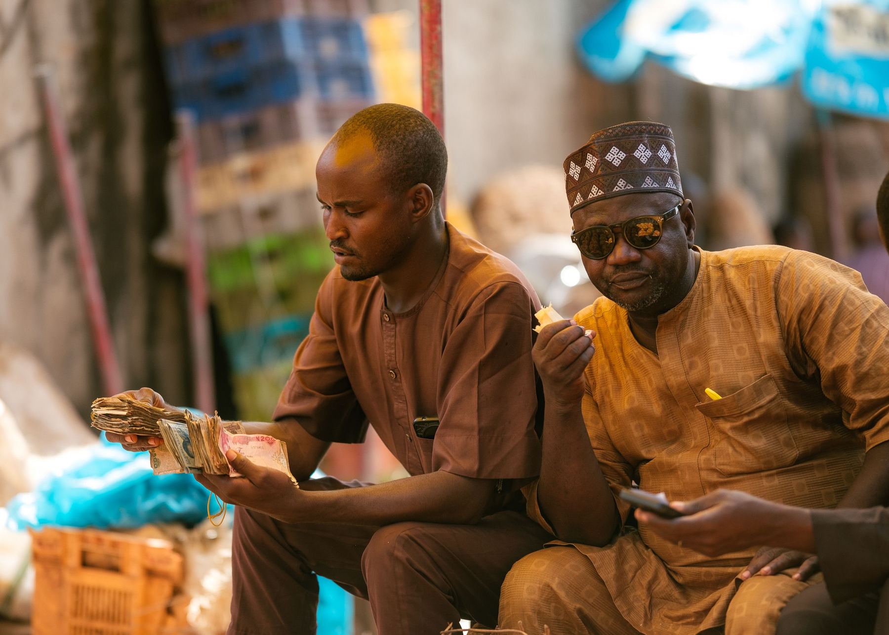 Two traders at a Nigerian market counting the day’s cash