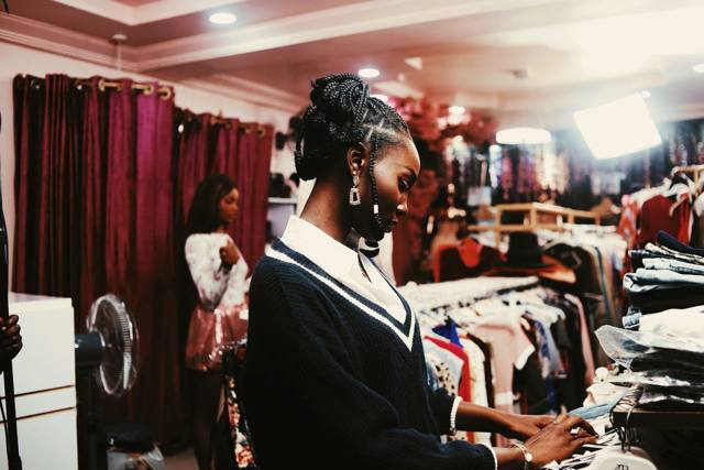 A shop owner writing at her counter in a clothing boutique