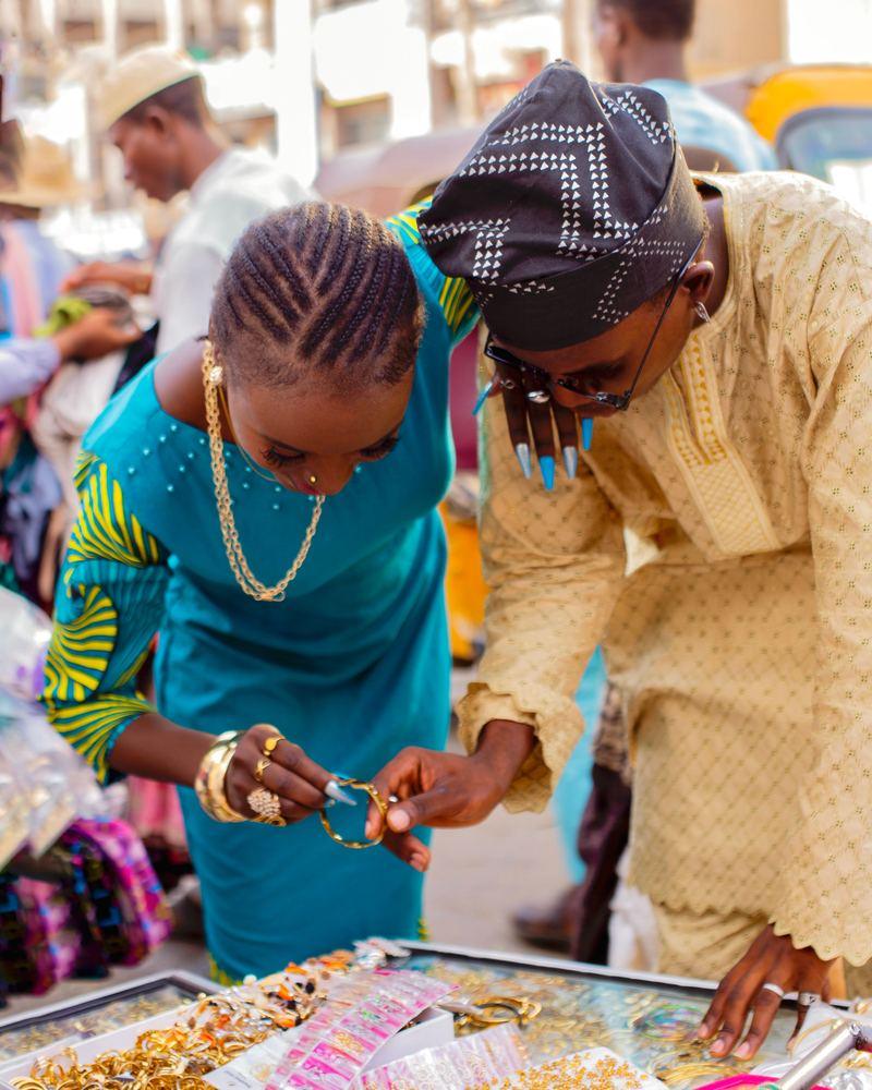 A trader showing jewellery to a customer at a market stall