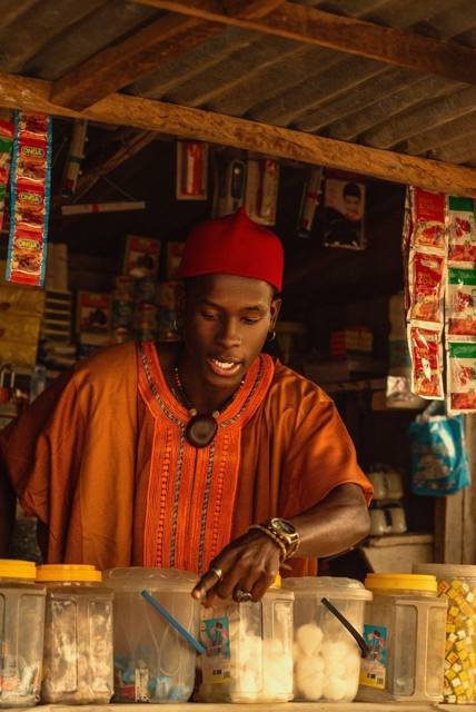 A trader at his kiosk, surrounded by jars of sweets and snacks